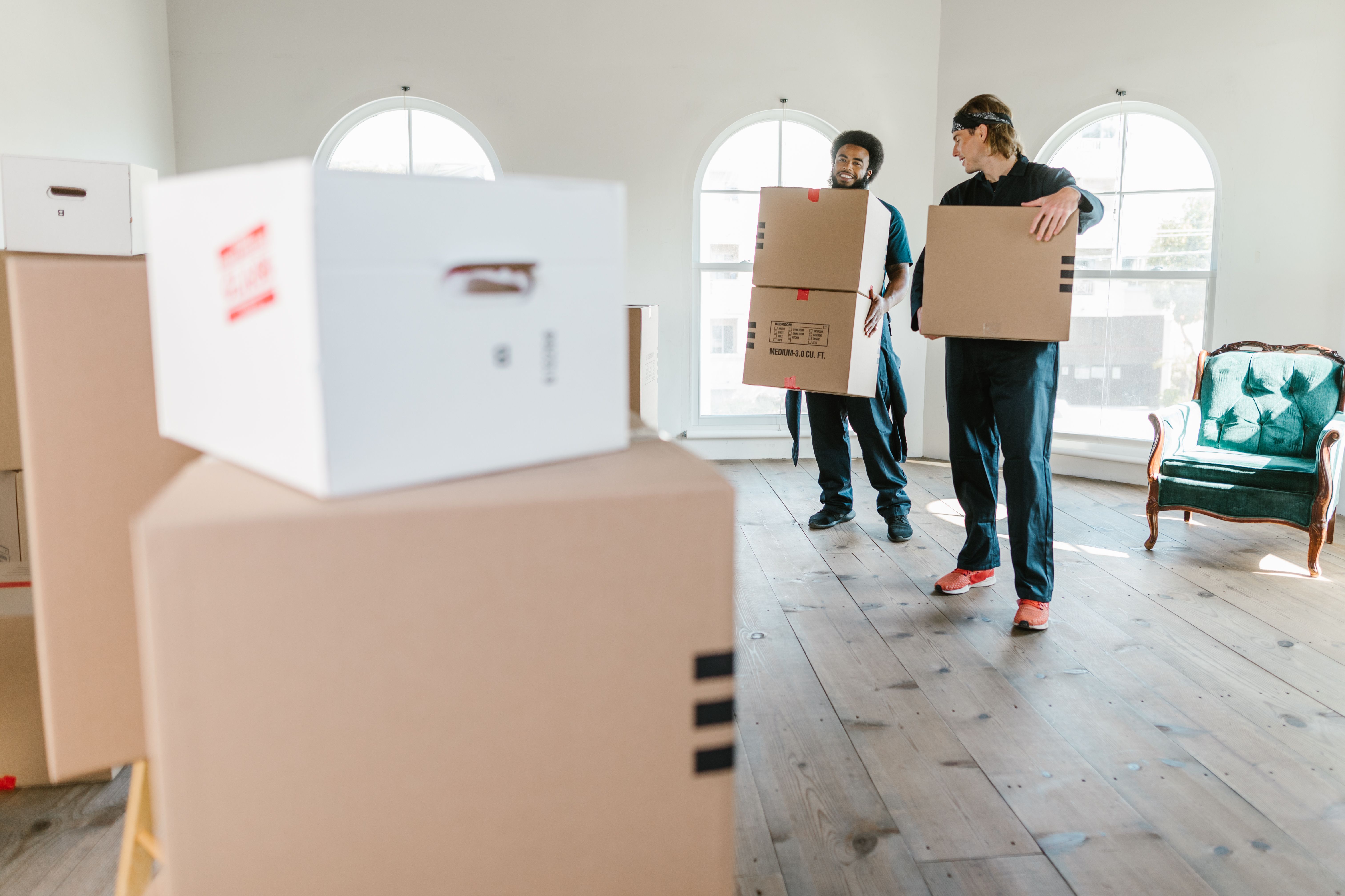 Two movers carrying boxes inside a bright home
